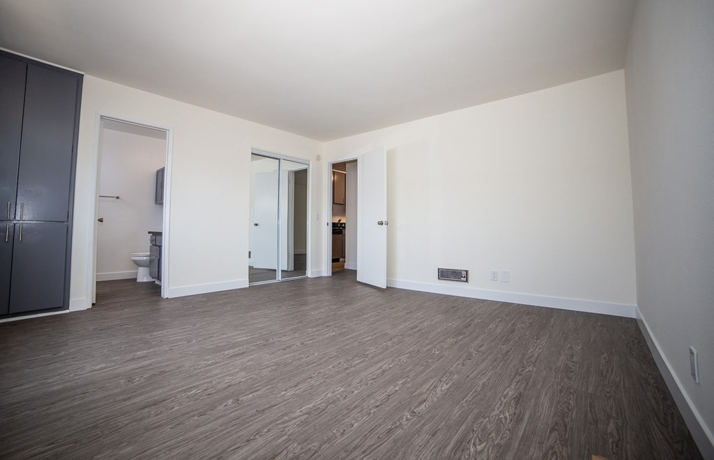 huge bedroom with white walls and hardwood floors