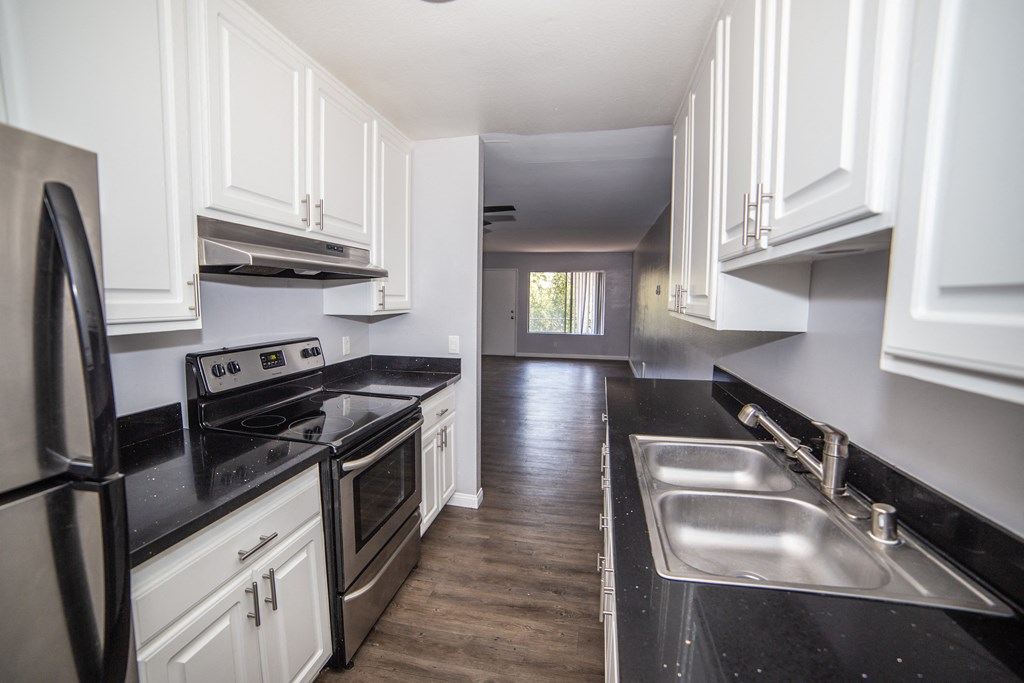 a 2 bedroom unit kitchen with white cabinets and black countertops