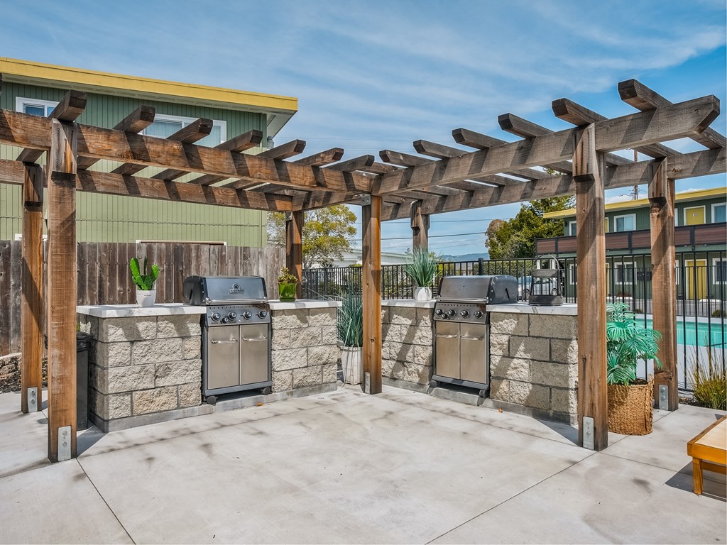 an outdoor kitchen with two stoves and a pergola