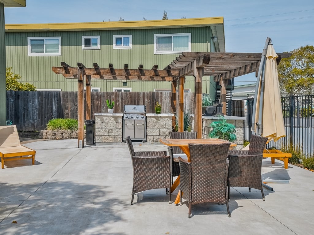 a patio with a table and chairs and a grill