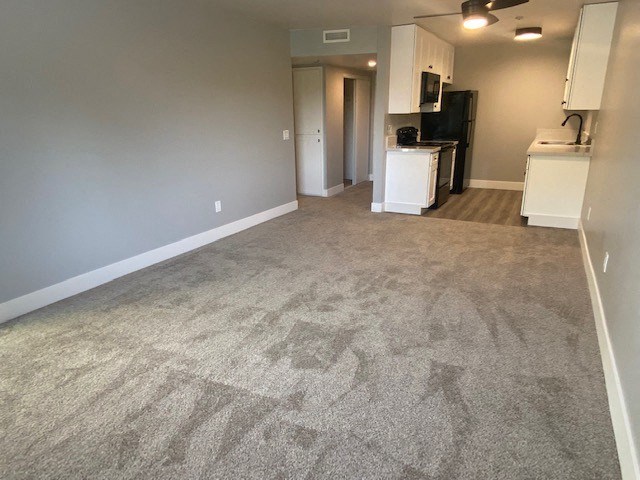 an empty living room with a kitchen in the background