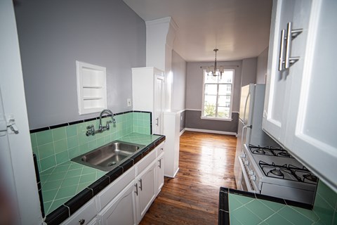 A kitchen with white cabinets and a green tile backsplash.