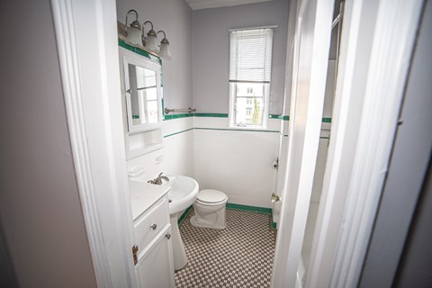 A bathroom with a toilet, sink, and mirror.