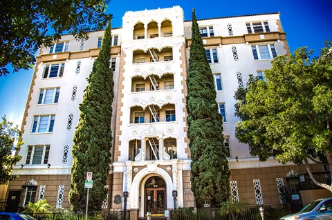 A tall building with a large arched doorway and balconies on the upper floors.