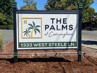 a sign in front of a building with a palm tree on it