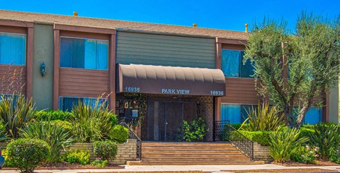 a brown building with a tan awning and stairs in front of it