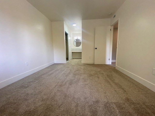 an empty room with a bathroom in the background