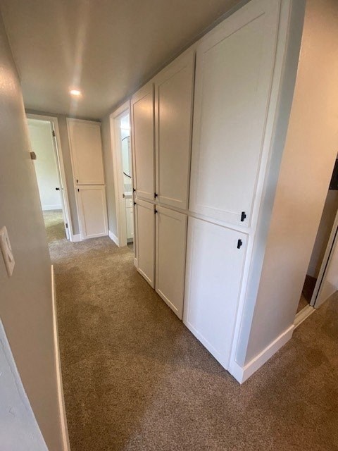 a hallway with white cabinets and a carpet