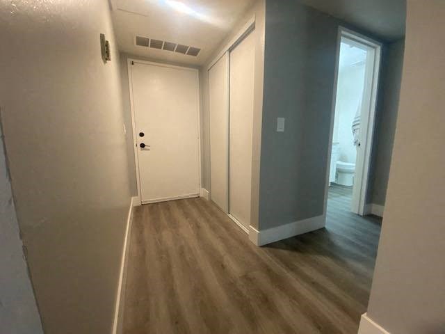 a hallway with a door and a toilet in the background