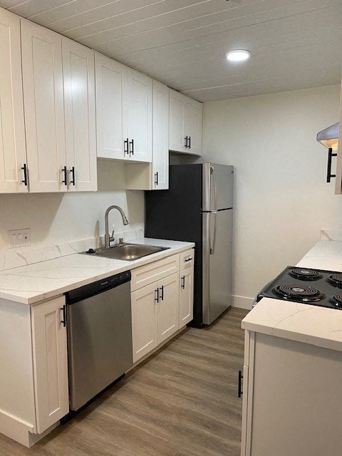 a kitchen with white cabinets and a black refrigerator