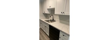 a kitchen with white cabinets and a black dishwasher