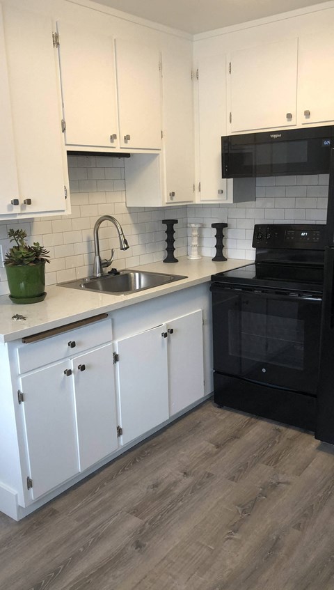 a kitchen with white cabinets and black appliances