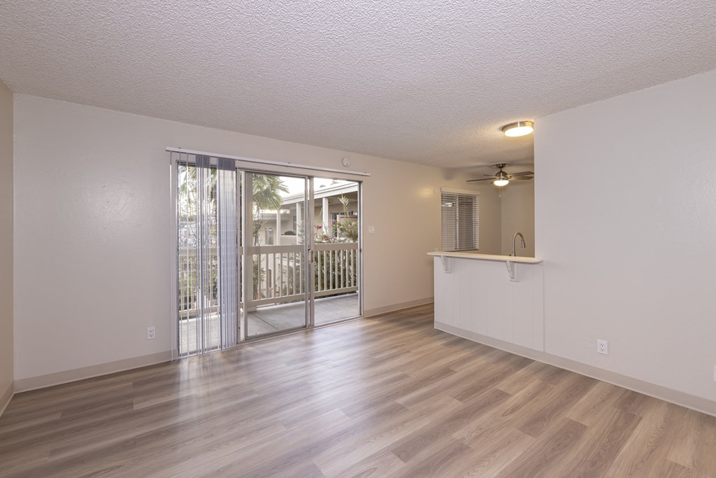 an empty living room with a sliding glass door to a balcony