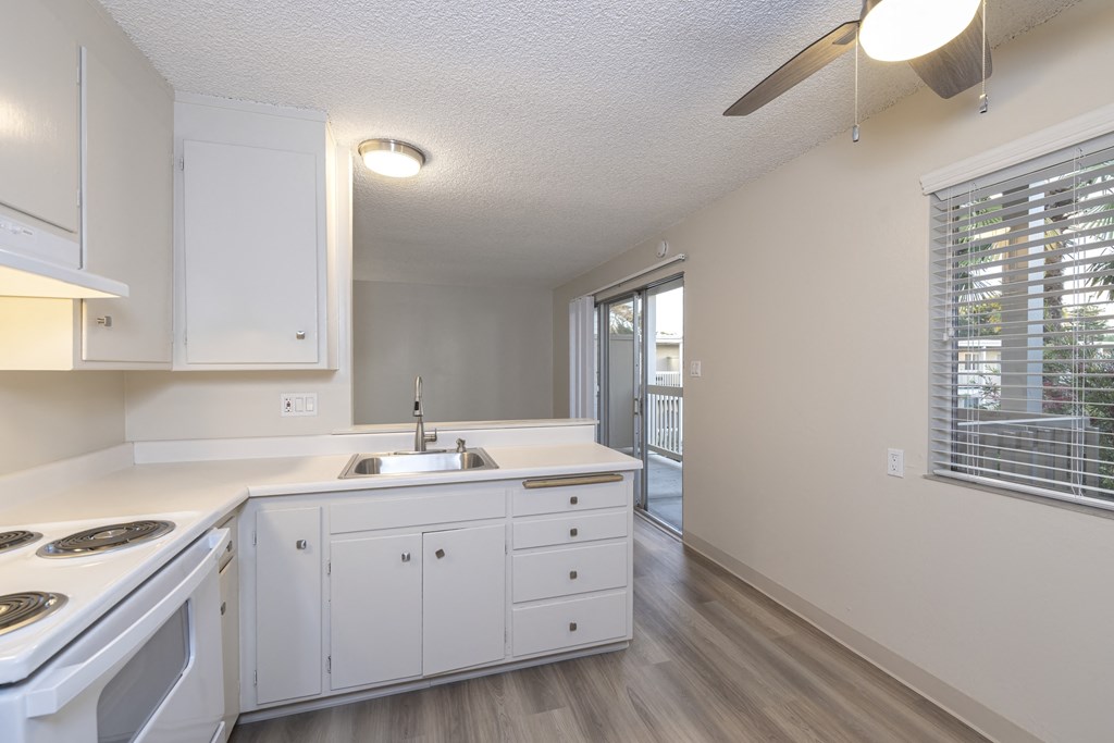 a kitchen with white cabinets and a sink and a window