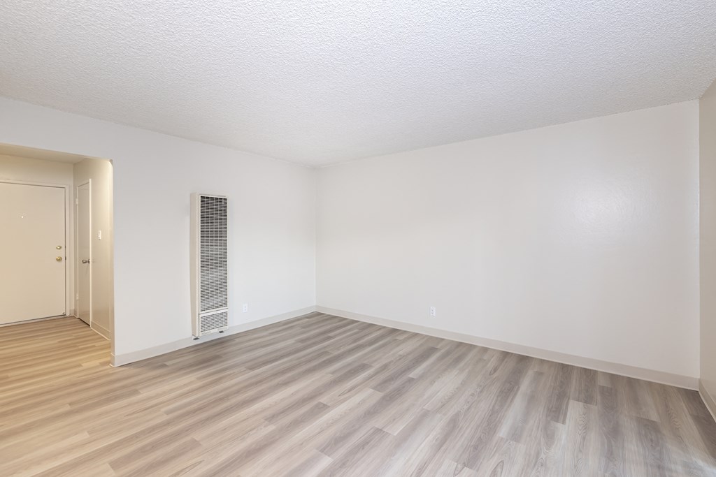 an empty living room with wood flooring and white walls