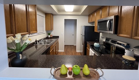 A kitchen with wooden cabinets and a tray of green and yellow apples.