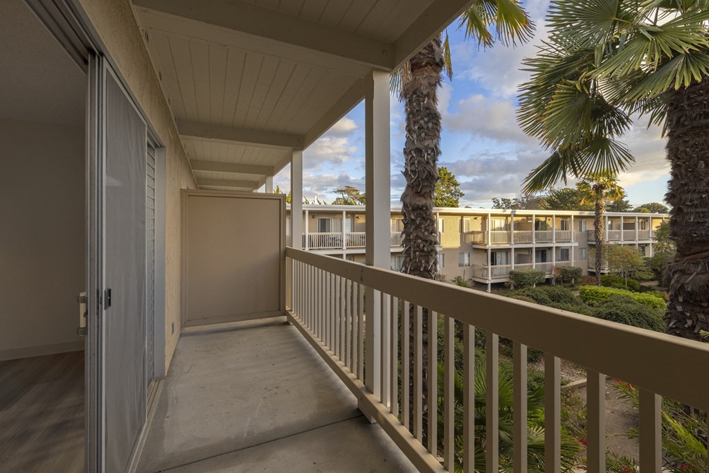 a balcony with a view of palm trees and condo buildings