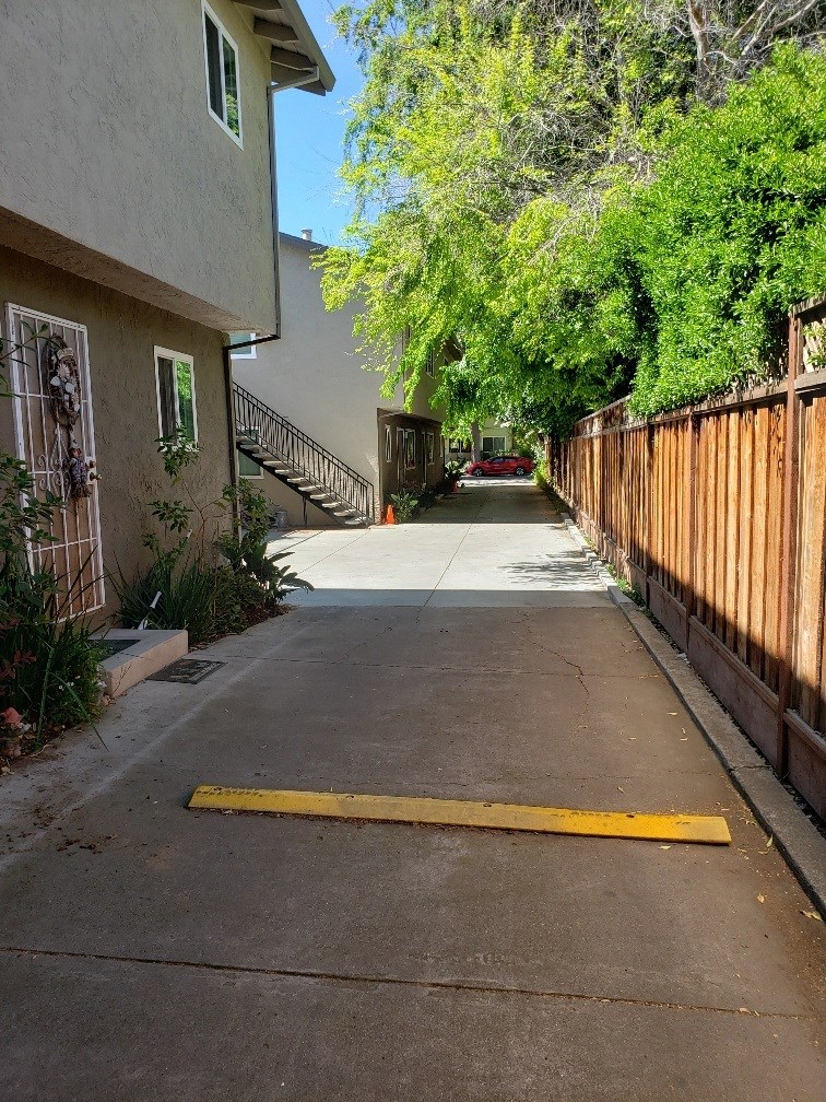 a driveway in front of a house with a wooden fence