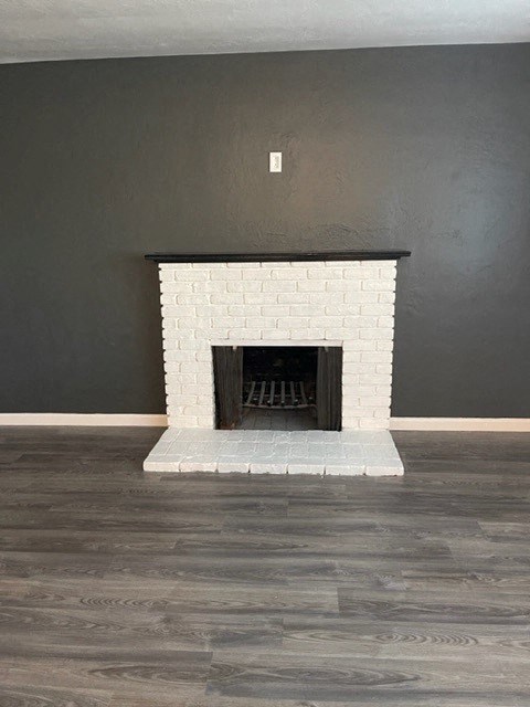 an empty living room with a white brick fireplace