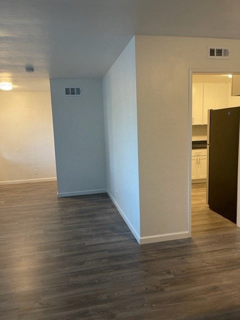 an empty living room and kitchen with a wood floor