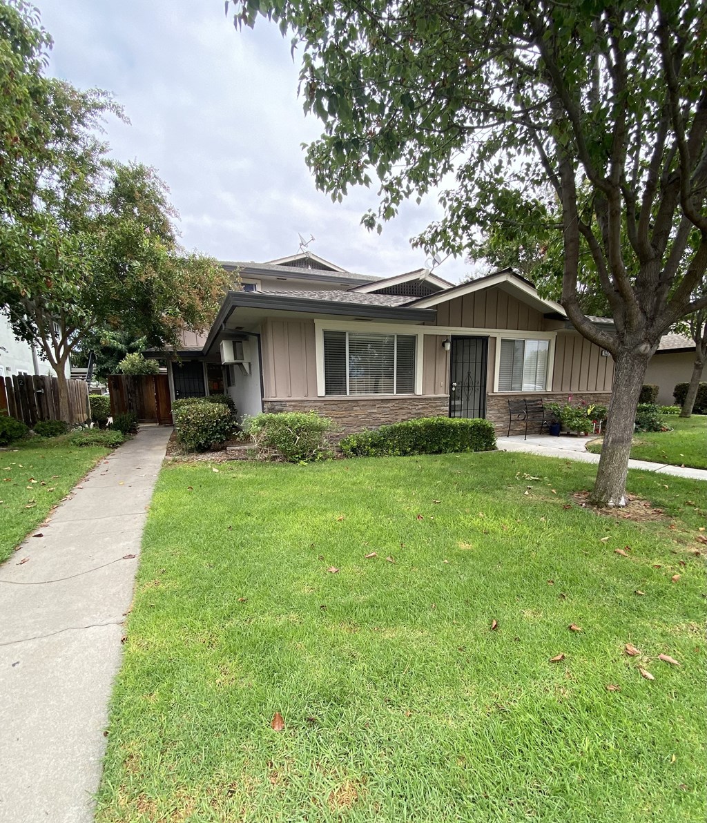 a house with a sidewalk and trees in front of it