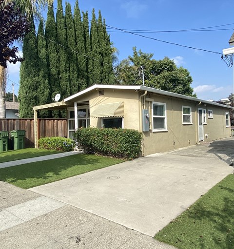 a small yellow house with a driveway and a yard