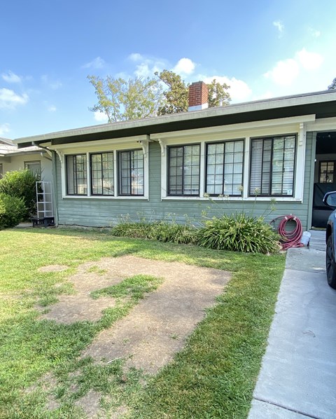 a blue house with a lawn and a sidewalk