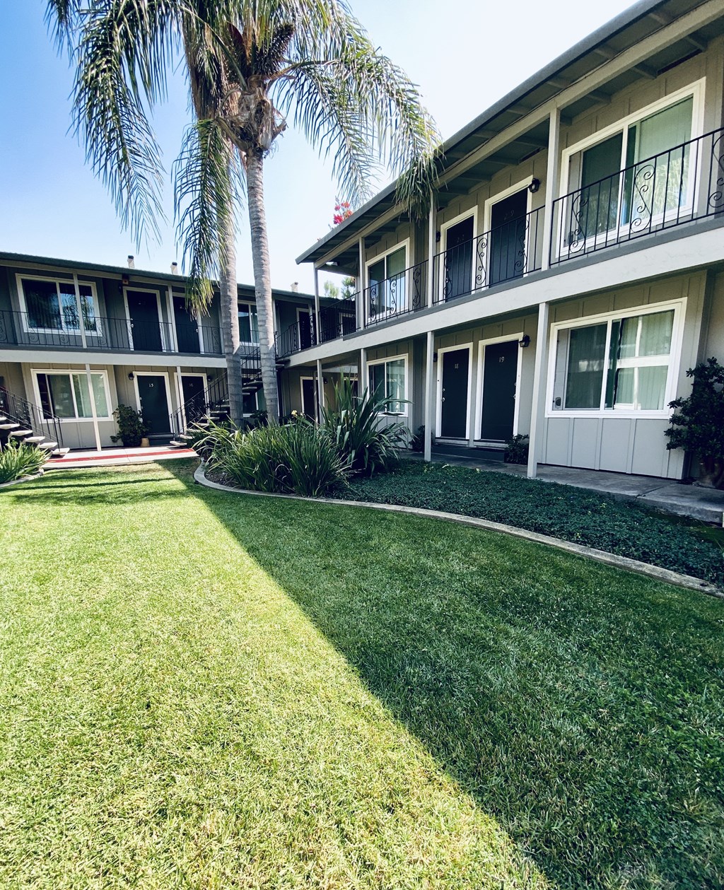 a yard in front of a building with grass and palm trees