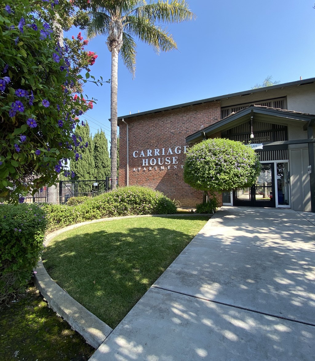 a sidewalk in front of a building with a sign that reads carriage house