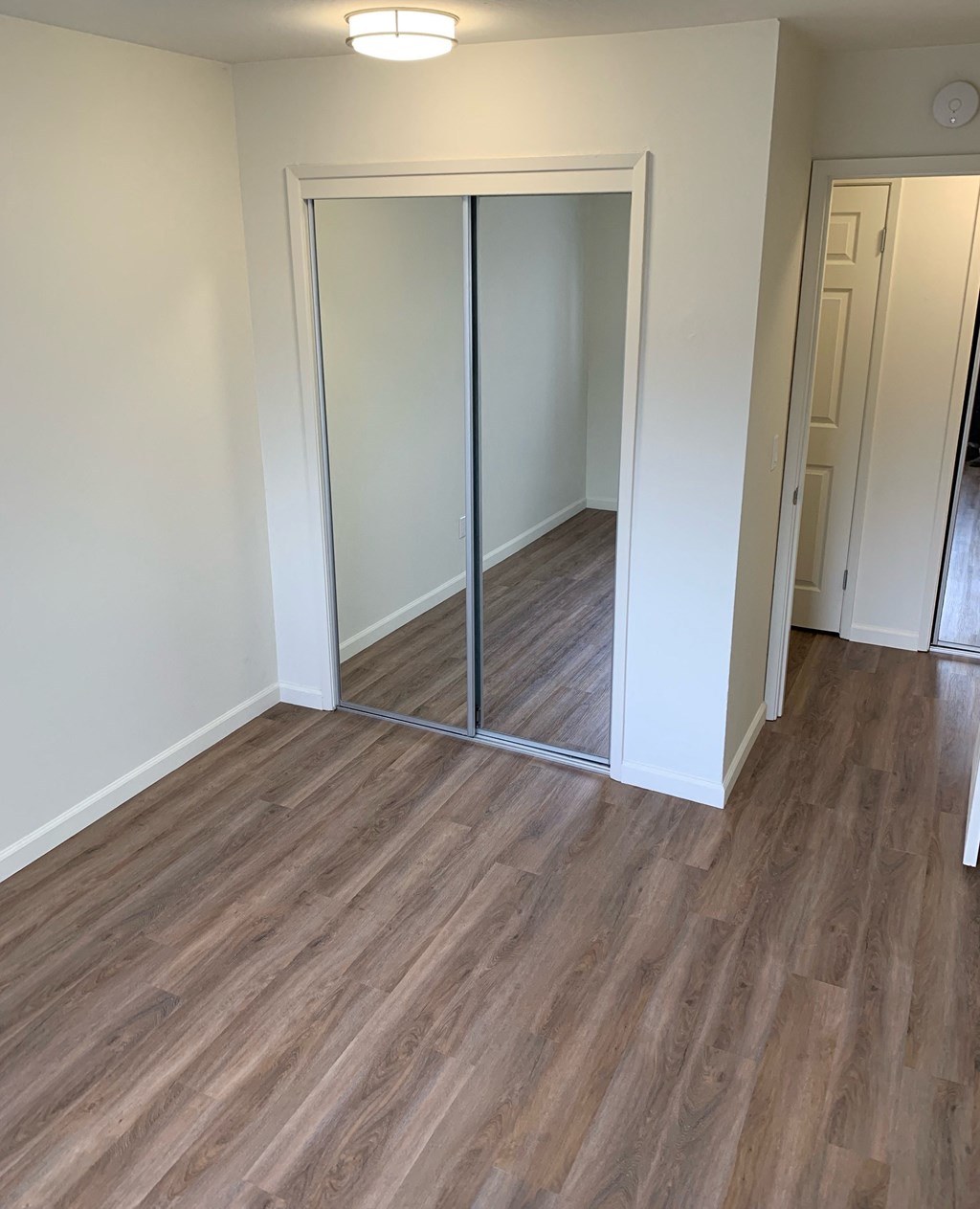 a living room with wood flooring and a mirrored closet