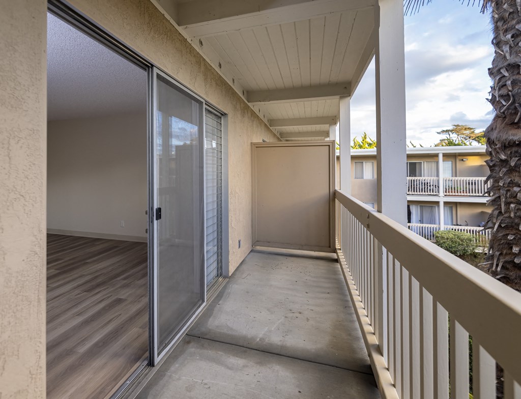 a covered patio with a sliding glass door to a balcony