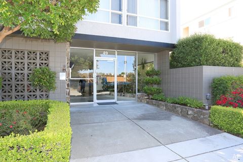 the entrance to an apartment building with glass doors and a sidewalk