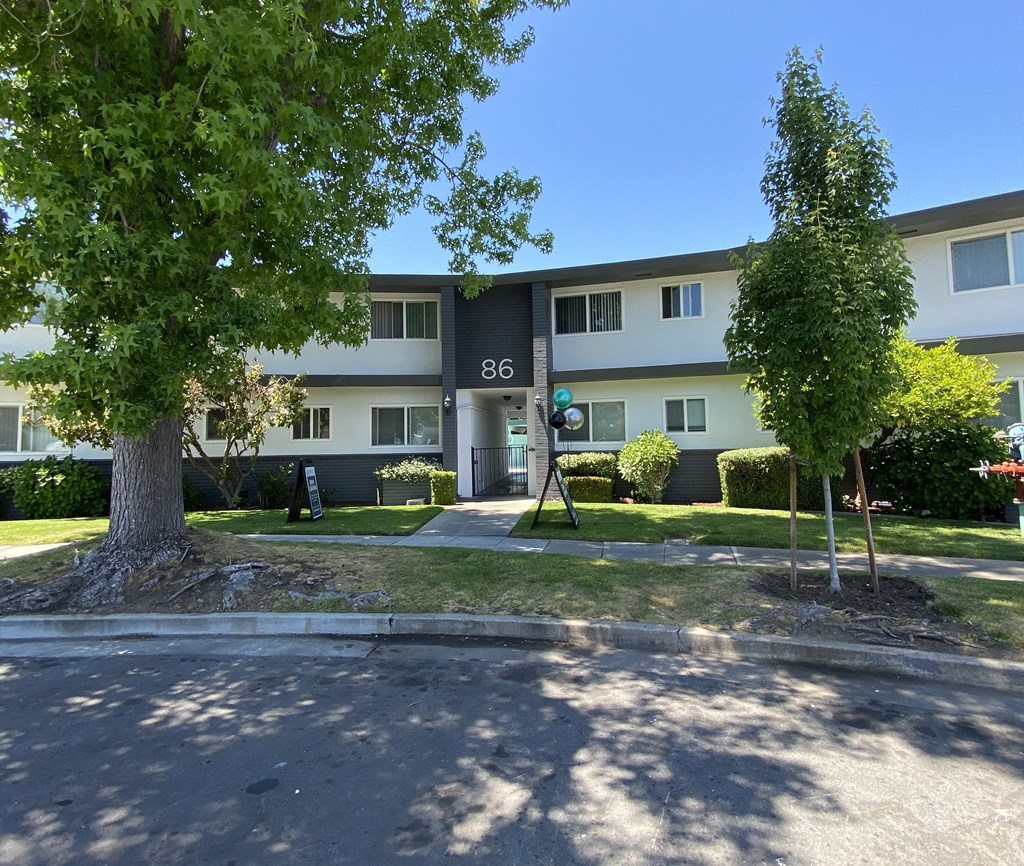 86 Renato Court Apartments building with a tree in front of it view from the roadway