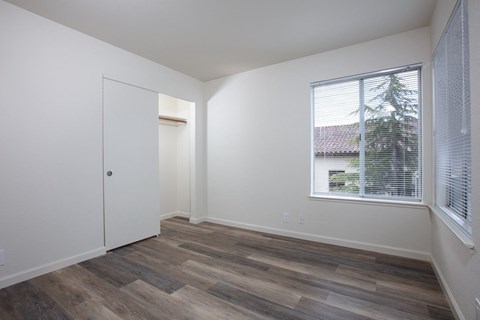 a bedroom with a large window and wood floors