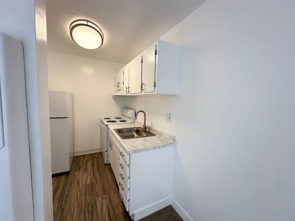 an empty kitchen with a sink and a refrigerator