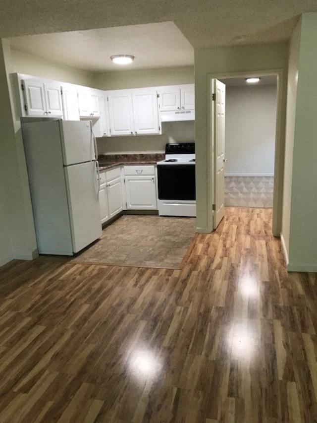 Colonial House Apartments San Jose an empty kitchen with white cabinets and a wood floor
