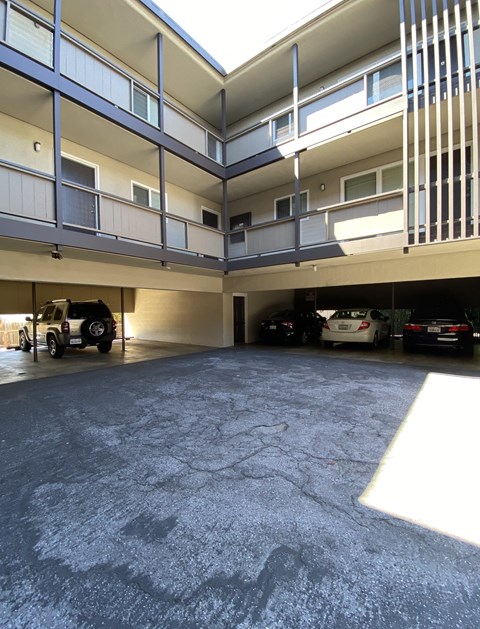 an empty parking lot with cars parked under a building