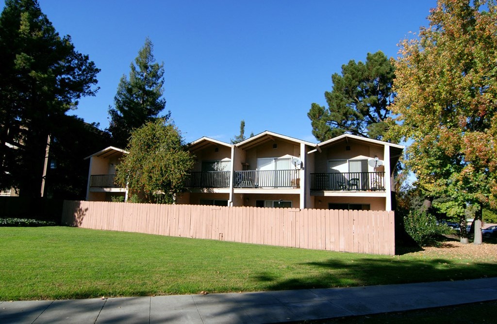The backside of the Aegena townhomes facing a green lawn and fenced in patios Prodesse Property Group 1211 Garbo Way  San Jose, CA 95117