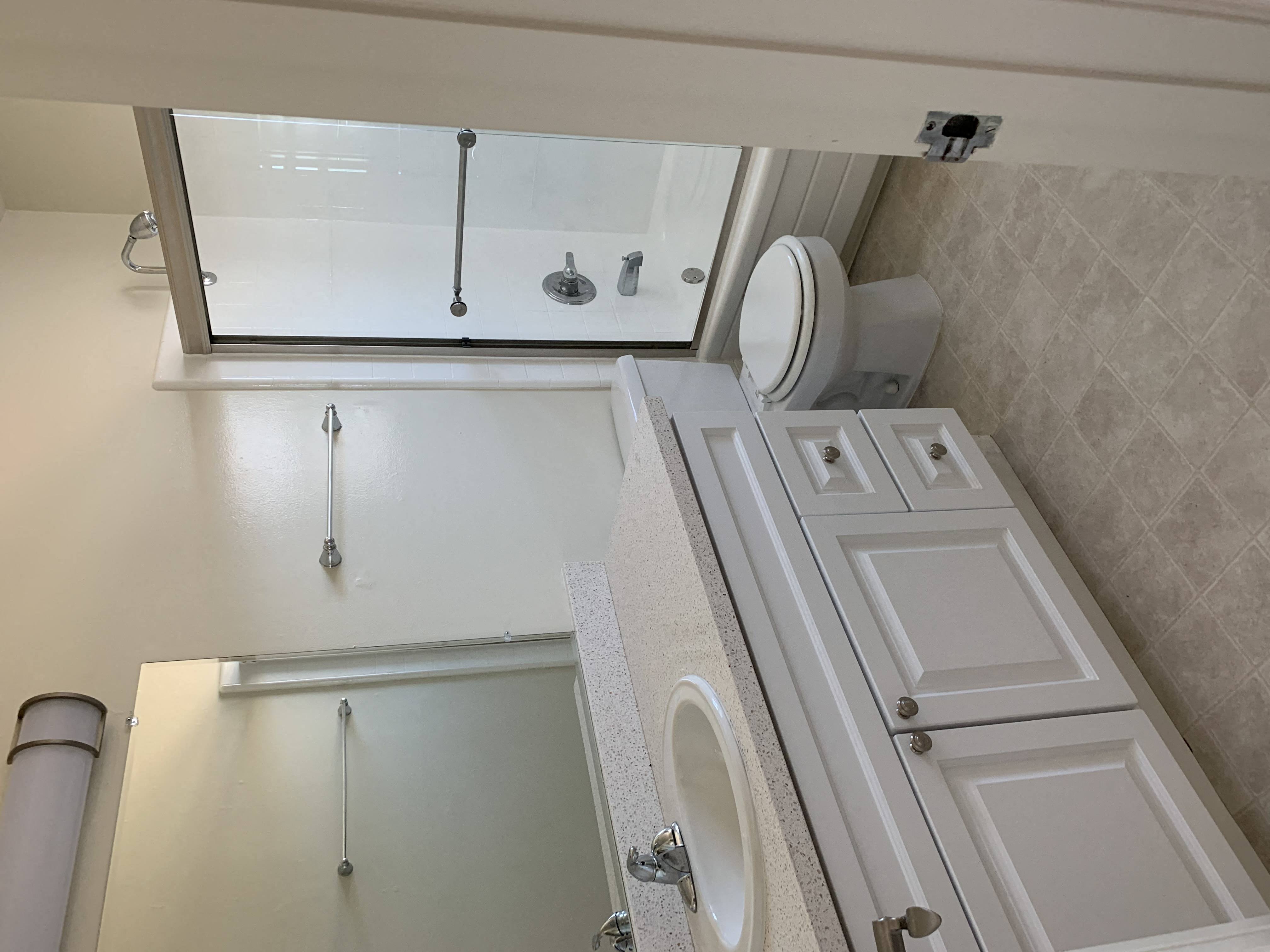 Bermuda Apts- white bathroom with vanity, toilet and shower door