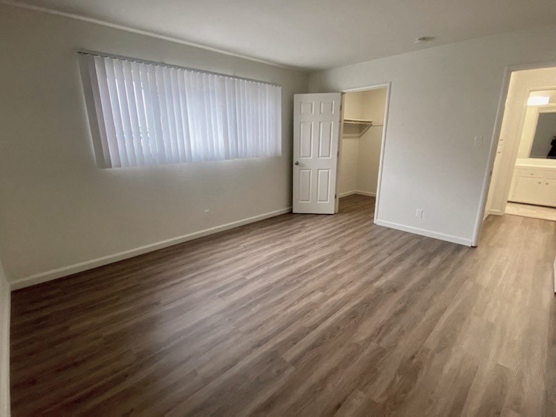 an empty living room with wood flooring and a window