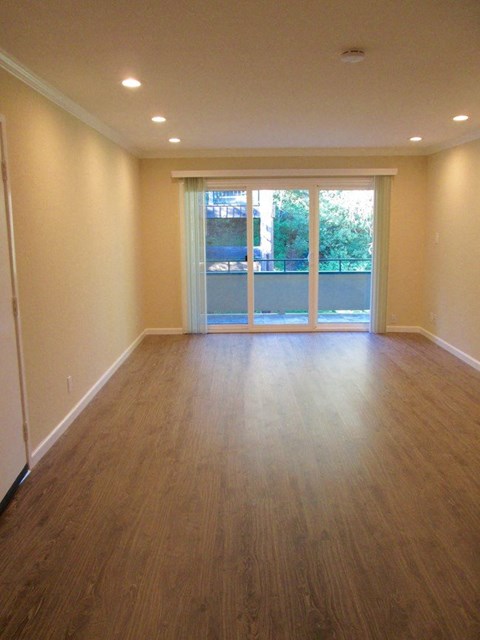 an empty living room with wood floors and a patio door