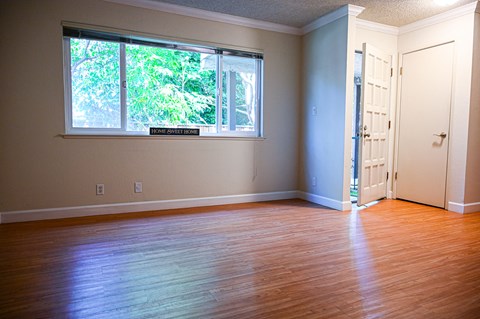 an empty room with a window and wooden floors