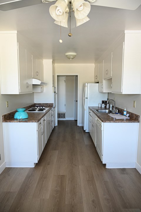 a kitchen with white cabinets and white appliances and wood floors