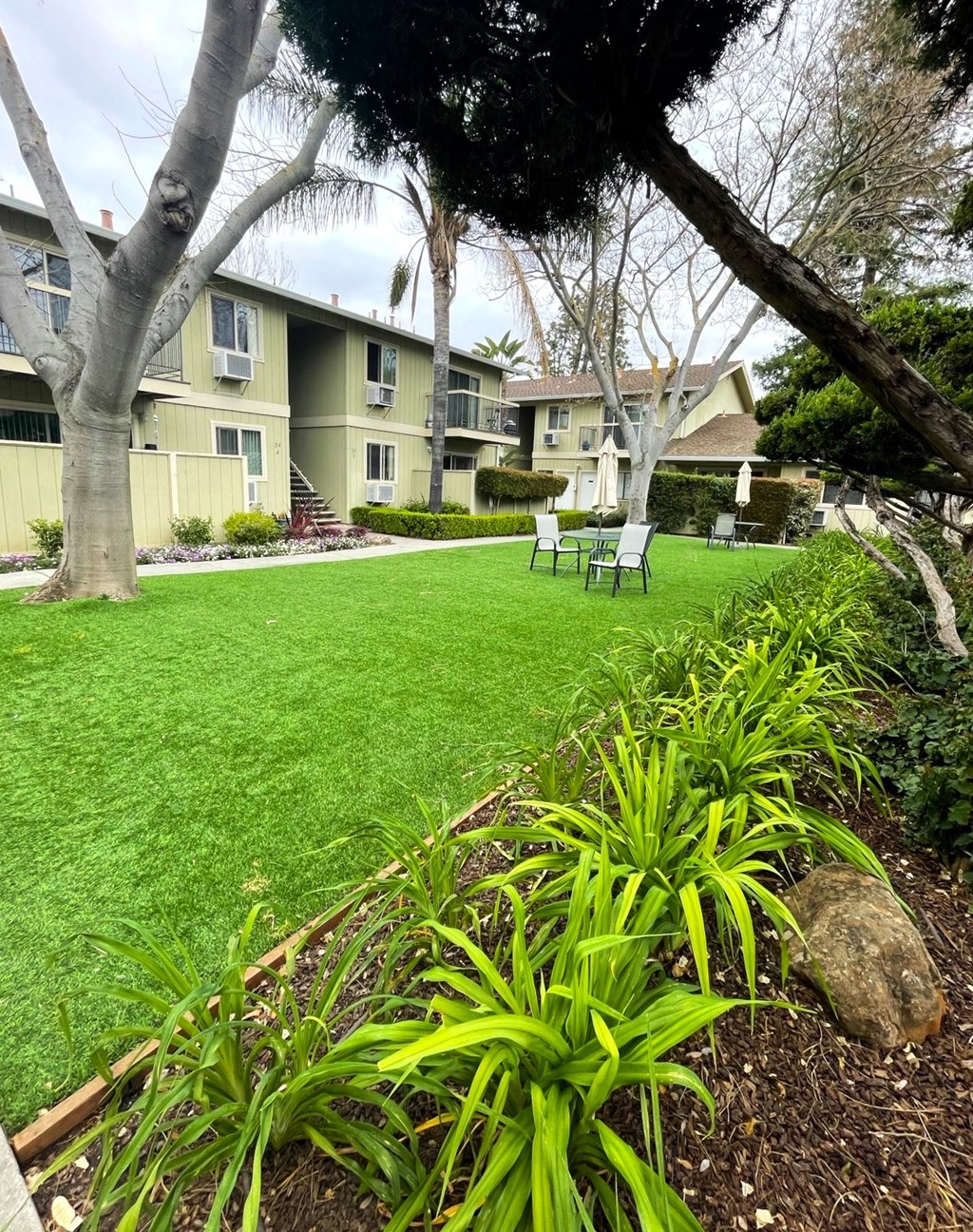 a yard with green grass and trees in front of a building