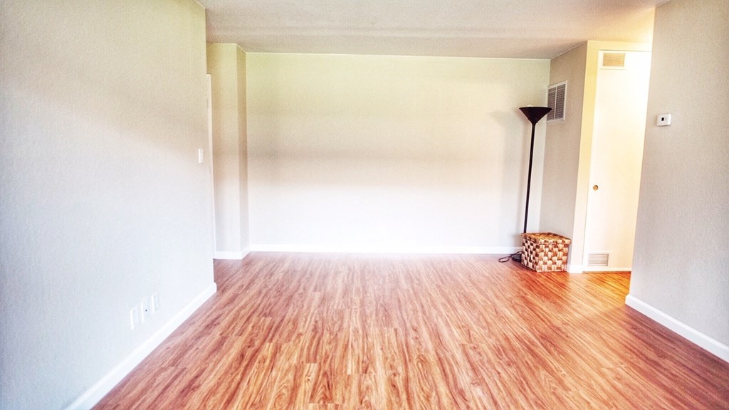an empty living room with wood floors and white walls