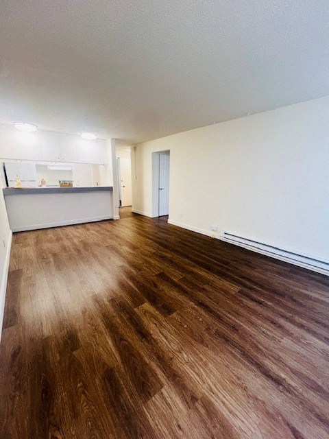 an empty living room and kitchen with wood floors