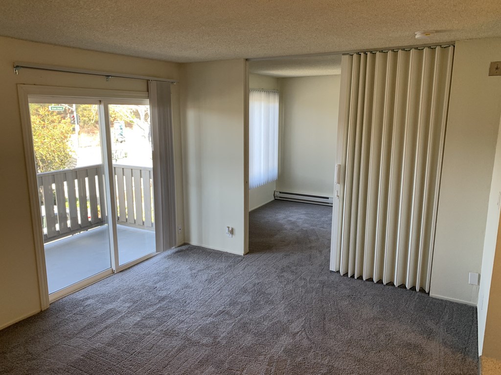 an empty living room with sliding glass doors to a balcony