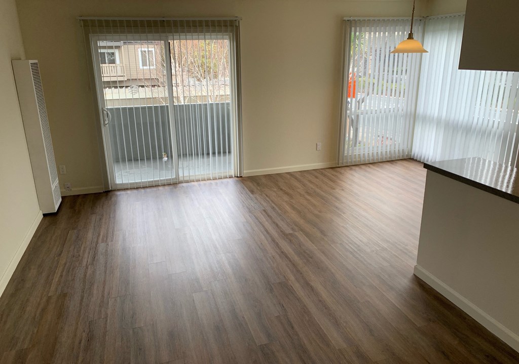 an empty living room with wood flooring and sliding glass doors