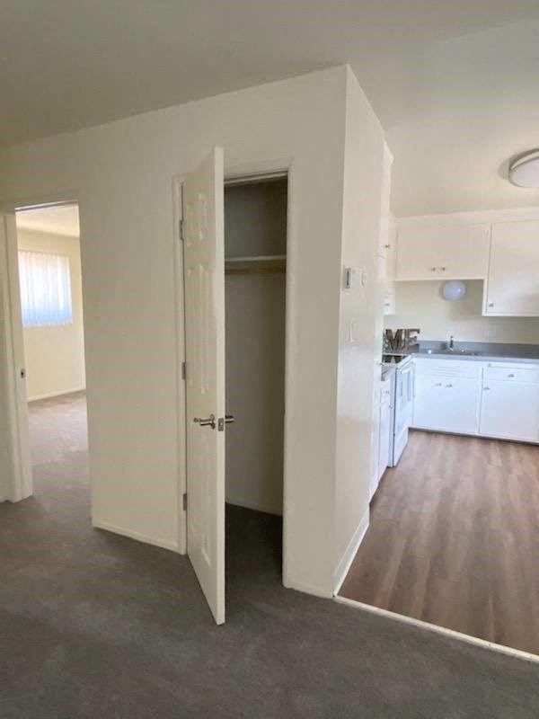an empty kitchen with white cabinets and a door open