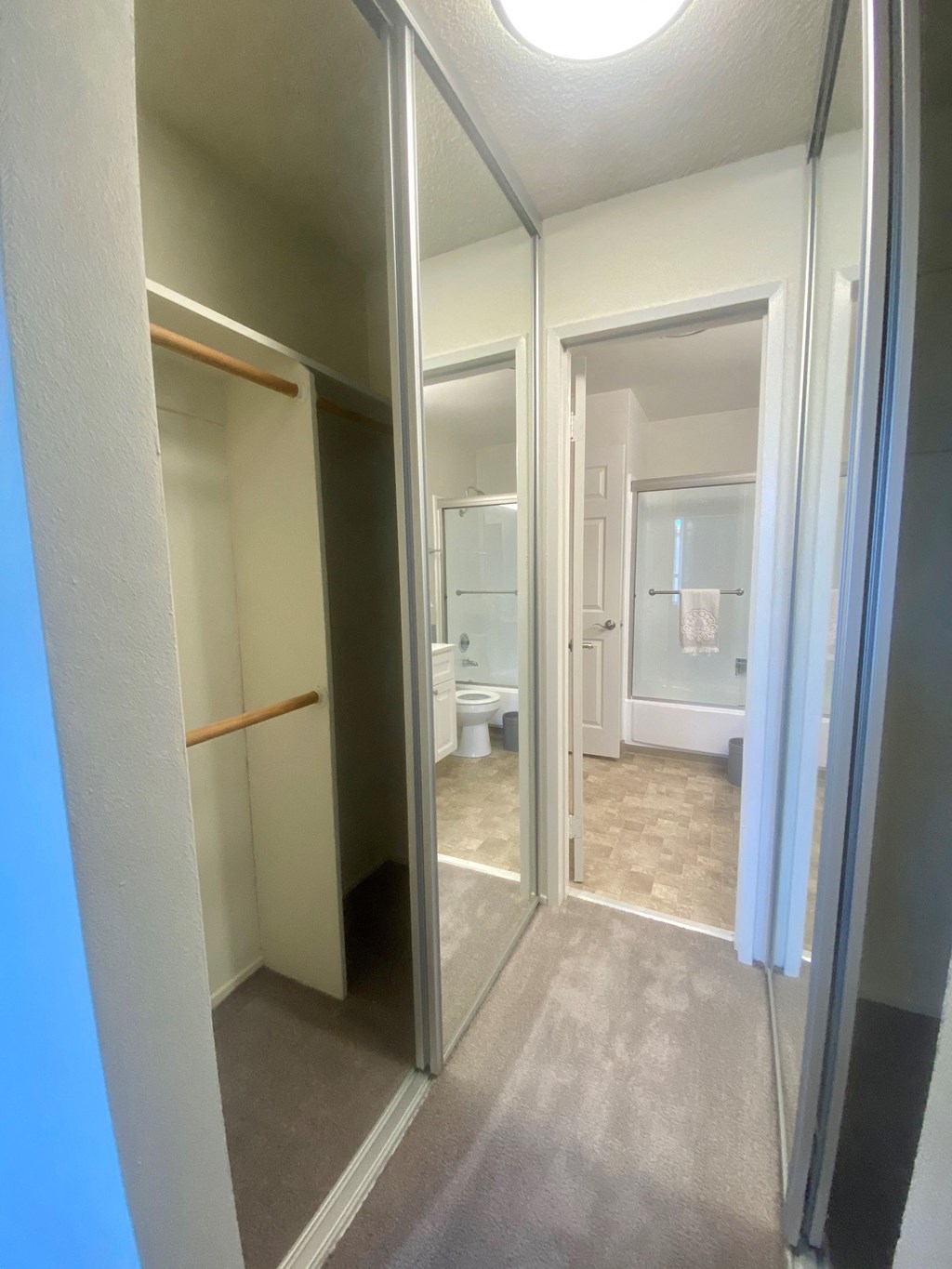 a hallway leading to the bathroom with closet doors on each side